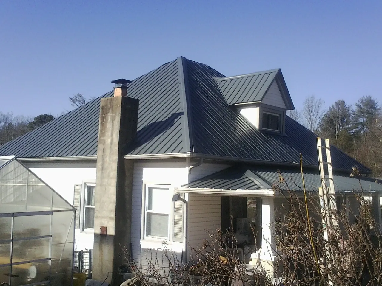 Dark blue standing seam metal roof on a white farmhouse with dormer — Slate & Tile Roof Repair by Roofing Brothers in Boonville