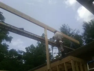 Carpenter setting a ridge beam over a new addition frame — Ice Dam Removal by Roofing Brothers in Boonville